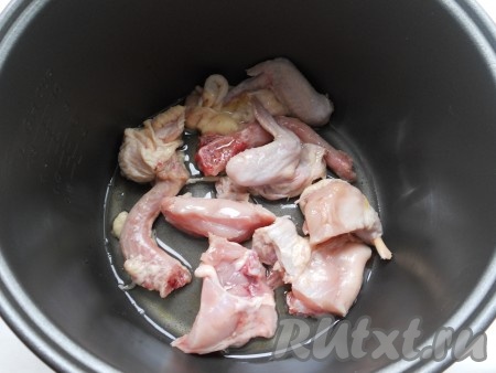 В чашу мультиварки влить растительное масло и выложить кусочки курицы. Выставить режим "Жарка" на 10 минут.
