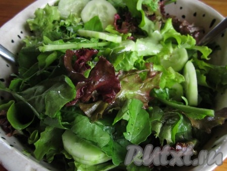 В глубокий салатник аккуратно порвите листья салата. Добавьте нарезанные огурцы и перемешайте.