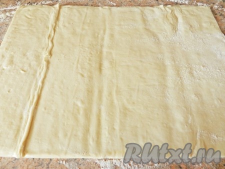 Слоеное тесто разморозить при комнатной температуре, развернуть на столе. Раскатать до толщины 3 мм и разрезать на одинаковые квадраты.