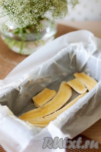 Подготовьте форму для выпечки и застелите ее бумагой, смазанной сливочным маслом. Разрежьте банан вдоль на три равные части и уложите их на дно формы.

