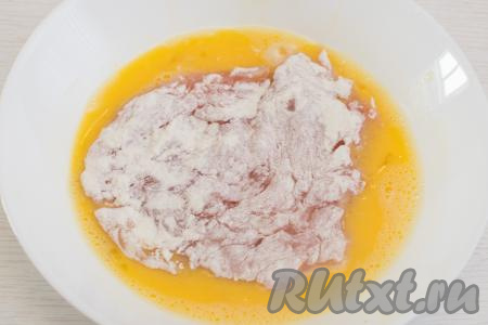 В отдельной тарелке взбить сырые яйца вилкой до однородности. Куриную отбивную, покрытую мукой, выложить во взбитые яйца.