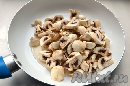 Шампиньоны помыть, если грибы крупные, тогда нарезать их на части помельче. В сковороду влить 1 столовую ложку растительного масла и выложить шампиньоны. Поставить сковороду на огонь. Во время обжаривания грибов выделится довольно много жидкости. Обжаривать грибы, помешивая, на среднем огне до испарения жидкости (обычно на это требуется 8-10 минут).
