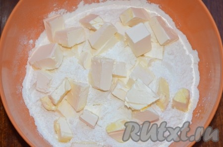 Приготовим тесто. В глубокую миску просейте муку, добавьте соль и разрыхлитель. Масло холодное, но не из морозилки, нарежьте кубиками и перетрите с мукой в крошку.
