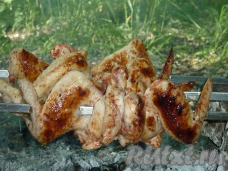 Жарить куриные крылышки на углях около получаса со всех сторон до красивой румяной корочки, периодически переворачивая и поливая томатным маринадом. 