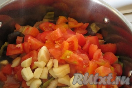 Чеснок крупно нарубить. Когда мясо будет почти готово, добавить в кастрюлю помидоры и чеснок. Тушить блюдо ещё минут 10-15, до полной готовности мяса.
