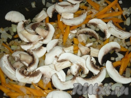 Через несколько минут добавляем грибы к луку и моркови.
