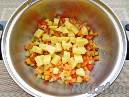 Переложить овощи в кастрюлю, добавить нарезанный кубиками картофель.