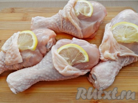 Куриные голени вымыть, обсушить. Отрезать 4 дольки лимона и поместить под шкурку каждой голени.
