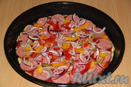 Луковицу очистить, удалить семена из болгарского перца. Лук и болгарский перец нарезать тонкой соломкой и выложить поверх колбасы.