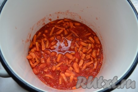 Томат вылить в большую кастрюлю, довести на небольшом огне до кипения. Высыпать в томат морковь и варить на слабом огне 15 минут.