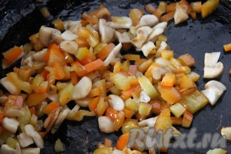 На сковороде обжарить очищенную и мелко нарезанную луковицу на растительном масле до золотистости (на это потребуется минуты 3). Болгарские перцы, очищенные от плодоножек и семян, нарезать на небольшие кубики. Шампиньоны нарезать достаточно мелко. Когда лук зазолотится, выложить к нему нарезанные перцы и шампиньоны, обжаривать на среднем огне, периодически помешивая, минут 7 (продолжительность обжарки перцев регулируйте по своему вкусу - если хотите, чтобы кусочки перчиков немного похрустывали, обжаривайте их немного меньше, если любите более мягкие овощи, обжаривайте их минут 8-9).
