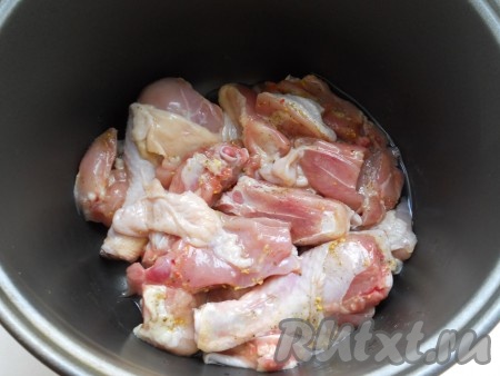 В чашу мультиварки влить растительное масло. Выложить куски курицы, посыпанные специями.