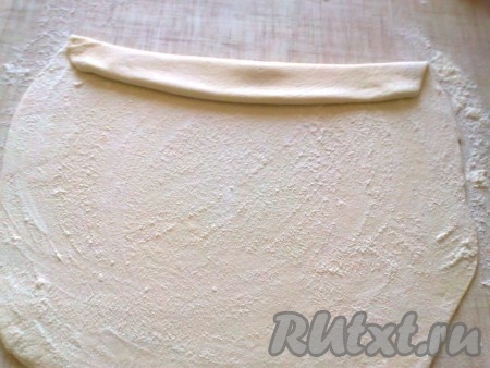 Раскатанное тесто хорошо посыпать мукой и не очень плотно свернуть в рулет шириной 2-3 см.
