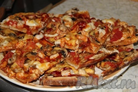 Наша домашняя пицца с куриной грудкой и грибами готова, разрезаем её на кусочки и подаём к столу. Дрожжевое тесто, замешанное на молоке,- очень удачное, пицца из него получается отменной!
