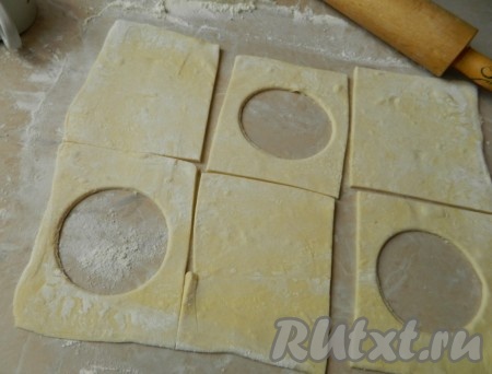 Бездрожжевое слоеное тесто размораживаем, немного раскатываем и режем на квадраты. В половине квадратиков вырезаем серединку.
