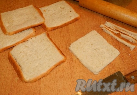 Каждый кусочек тостового хлеба хорошо раскатываем скалкой. Корочки отрезаем.
