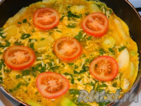 Кабачки, обжаренные до полуготовности, залить яично-сырной смесью. Сверху разложить помидор, порезанный кружочками, и накрыть сковороду крышкой. Фриттату с кабачками жарить до готовности яиц (минут 10-15). 
