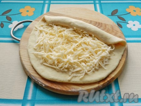 На лепешку выложить сыр, оставив свободными края. Каждую лепешку с двух сторон скрутить валиком.