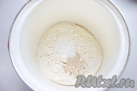 Муку просеять в миску, добавить дрожжи, сахар и соль, перемешать.
