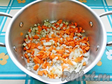 Разогреть растительное масло в кастрюле с толстым дном, выложить лук и морковь, обжарить их в течение 5 минут на среднем огне, иногда помешивая.
