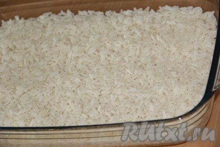 В жаропрочную форму выложить рис и разровнять.