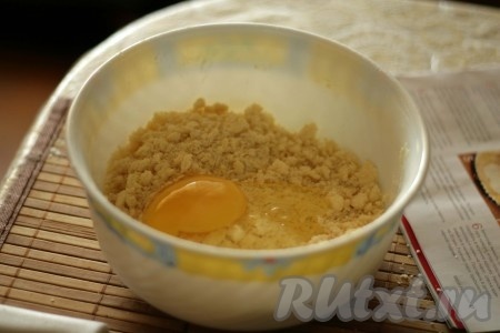 В просеянную муку с солью добавить нарезанное на кусочки холодное сливочное масло. Растереть смесь в крошку. Добавить яйцо.
