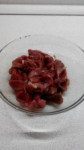 Мясо нарезать тонкими пластинками поперек волокон и замариновать в соевом соусе с добавлением соли и перца в течение получаса.
