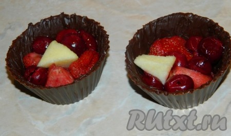 В получившиеся шоколадные корзиночки выложить ягоды или фрукты. Если ягоды и фрукты замороженные - разморозить.