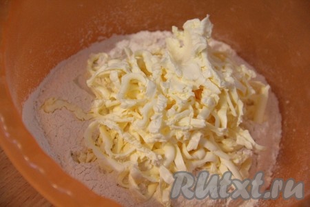 Просеянную муку, разрыхлитель и соль насыпать в глубокую миску, добавить натёртый на крупной тёрке или порубленный на мелкие кусочки маргарин. Перетереть маргарин с мукой в крошку.
