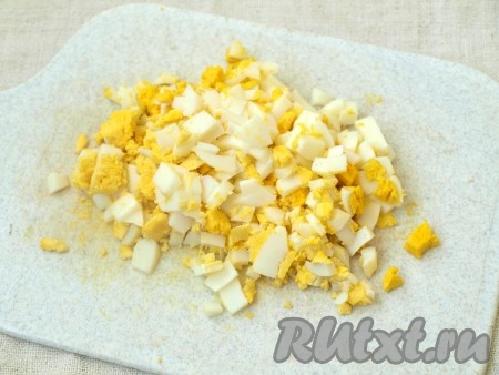 Яйца нарезаем кубиками (один яичный желток оставляем для приготовления заправки).
