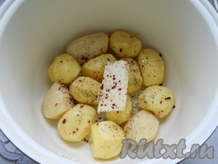 Выложить подготовленный картофель в чашу мультиварки. Посолить, посыпать специями и черным молотым перцем. Добавить сливочное масло.