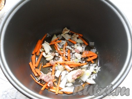 В чашу мультиварки влить растительное масло. Лук порезать средними кусочками, морковь - соломкой или брусочками. Выложить в чашу половину лука и моркови, немного жира из тушенки.
