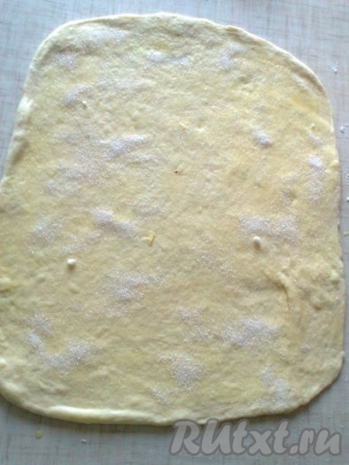 Из другой части теста можно приготовить плюшки в виде розочек. Для этого раскатываем тесто в виде прямоугольника и смазываем его растительным маслом, посыпаем сахаром.
