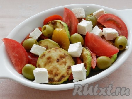 Добавить в салат к кабачкам и перцу нарезанные дольками помидоры, оливки и кубики сыра Фета. Заправить заправкой, посыпать зеленью и подавать.
