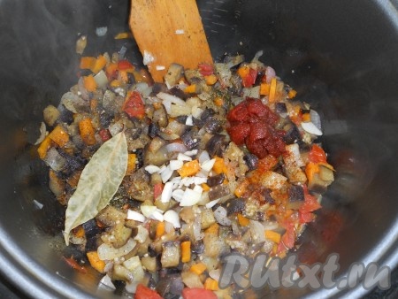 К овощам добавить томатную пасту, посолить и поперчить по вкусу, посыпать специями. Также добавить лавровый лист и измельченный чеснок, влить воду. 