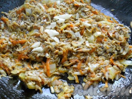 Добавить в сковороду к овощам шампиньоны и обжаривать все вместе, помешивая, до того момента, когда жидкость, выделившаяся из шампиньонов, выпарится. Затем добавить измельченный чеснок, перемешать и выключить газ.
