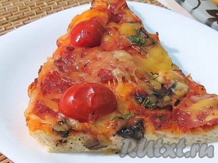 Вкуснейшую домашнюю пиццу с колбасой, помидорами, сыром и грибами нарезаем на кусочки и подаём к столу.