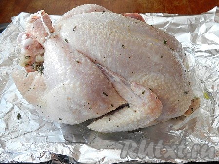 Вложить четвертинки лимона вместе с оставшимся тимьяном внутрь курицы. Ножки связать, крылышки прикрепить к тушке (прорезать небольшие кармашки на коже и вставить в них крылышки). Форму для выпечки застелить фольгой, положить курицу в форму грудкой вверх и поставить в нагретую до 200 градусов духовку на 45 минут. Затем включить режим гриль и увеличить температуру до 220 градусов. Запекать еще 10-15 минут до хрустящей золотистой корочки. Чтобы проверить готовность курицы, проткните ее тонким ножом - вытекающий из мяса сок должен быть прозрачным.