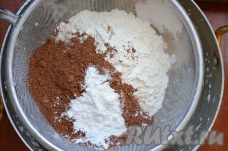 Затем добавить сметану, перемешать тесто. Просеять какао-порошок, разрыхлитель и муку в тесто, перемешать. Муку добавляйте постепенно, проверяя консистенцию теста. Тесто должно получиться  средней густоты.