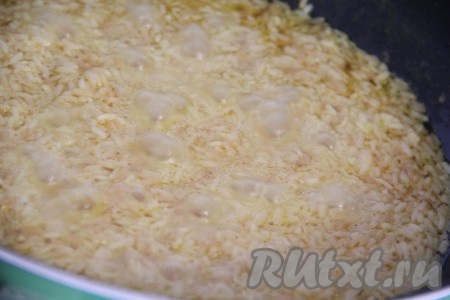 Оставить рис кипеть без крышки, пока вода с поверхности не впитается. Как только рис оголится, убавить огонь до минимума, накрыть сковороду крышкой и готовить 20 минут.