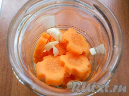 В чистую сухую баночку выкладывать кружки моркови вместе с нарезанным крупными кусочками чесноком.
