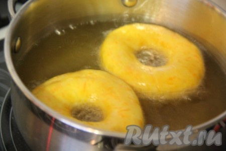 Растительное масло влить в кастрюльку и хорошо разогреть. Аккуратно опускать пончики в масло и жарить их с двух сторон до золотистого цвета.
