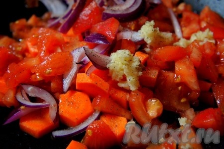 Нарезанные морковь, лук и помидоры выложить на сковороду, добавить пропущенный через пресс чеснок, перец чили, паприку, чёрный молотый перец, 3-4 столовые ложки воды, перемешать, накрыть сковороду крышкой и потушить овощи 5-7 минут с момента закипания воды на небольшом огне, периодически помешивая.
