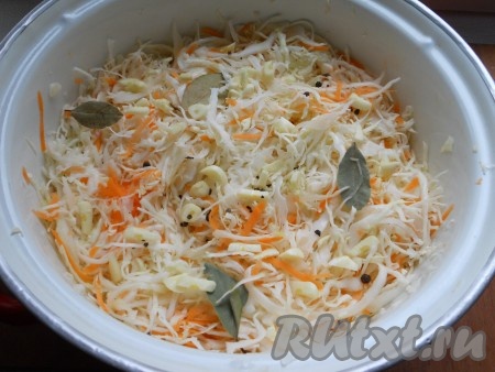 Перемешать капусту с морковью. Сверху поместить лавровый лист, черный перец горошком и нарезанный чеснок.
