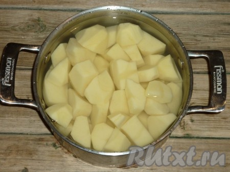 В кастрюлю выложить очищенный и нарезанный кусочками картофель, залить водой и поставить вариться. Когда вода в кастрюле закипит, нужно снять пену, картошку посолить и варить до готовности.
