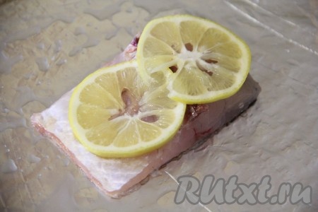 Лимон вымыть, обсушить и нарезать на тонкие кружочки. Выложить пару кружков лимона на рыбу.
