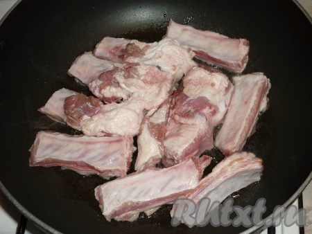 Свиные рёбрышки вымыть и нарезать на порционные кусочки. Разогреть на сковороде небольшое количество растительного масла, выложить свиные рёбра.