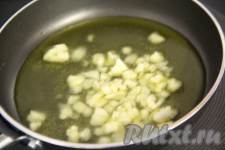 Оливковое масло влить в сотейник или сковороду. Чеснок почистить и нарезать тонкими лепестками. Масло разогреть, затем добавить измельченный чеснок и обжарить в течение 1 минуты. 