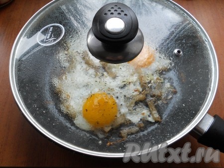 Жарить яйца до тех пор, пока не свернется белок, затем газ выключить и накрыть сковороду крышкой. Оставить яичницу с салом под крышкой на 2-6 минут (время зависит от того, какой консистенции желтки вы любите).
