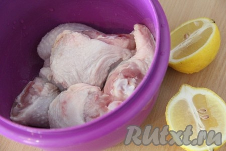 Курицу вымыть, обсушить бумажным полотенцем, разрезать на порционные кусочки и выложить в глубокую миску. Лимон вымыть и разрезать. 
